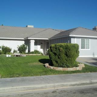 A suburban house with a well-maintained lawn under a clear blue sky.