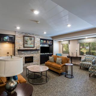 A modern and cozy living room featuring a stone fireplace, comfortable seating, and large windows.
