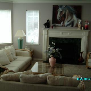 A cozy living room with a sofa, coffee table, and a fireplace adorned with artwork and decor.