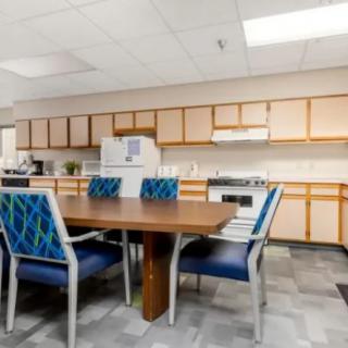 A kitchen space with a dining table and chairs, surrounded by cabinets and appliances.