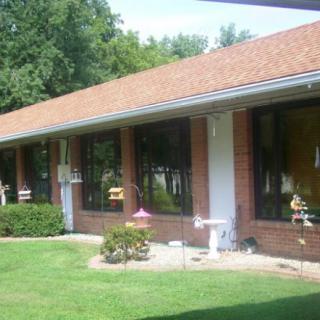 A brick building with large windows and a well-maintained lawn.