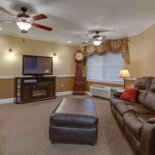 A cozy living room with a large sofa, coffee table, ceiling fans, and a television.
