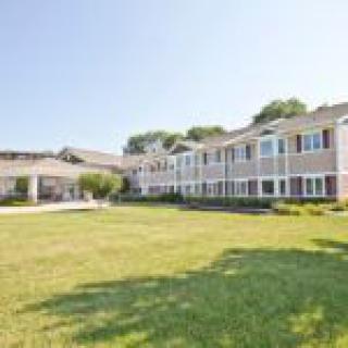 A large residential building with a well-maintained lawn under a clear blue sky.