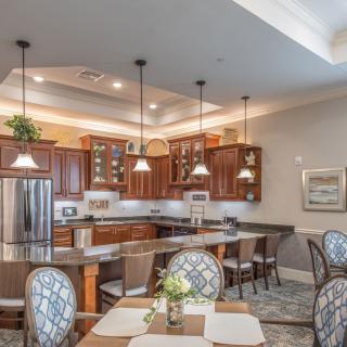 A modern kitchen with wood cabinets, pendant lighting, and a connected dining area.