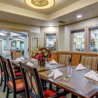 An elegantly set dining room table with neatly arranged chairs and a floral centerpiece.