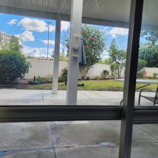 A serene outdoor view through a window, featuring bright blue skies and well-maintained greenery.