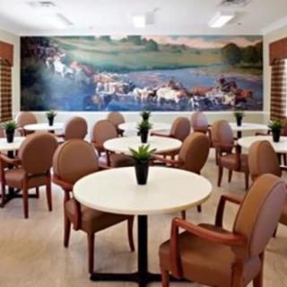 A well-arranged dining area with tables and chairs, featuring a scenic mural on the wall.