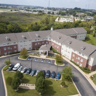 Aerial view of a residential building with a parking lot in a suburban area surrounded by greenery.