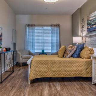 A cozy modern bedroom with wooden flooring, featuring a neatly made bed and decorative accents.
