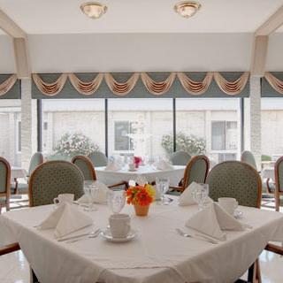 A beautifully arranged dining area with floral decorations and an elegant table setting, illuminated by natural light.
