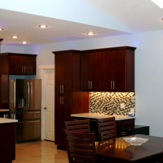 A modern kitchen featuring dark wood cabinets, stainless steel appliances, and a stylish backsplash.