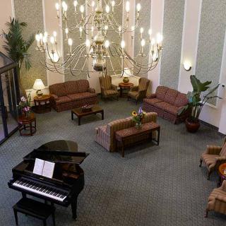 A spacious lobby featuring a grand piano, elegant chandelier, and comfortable seating area.