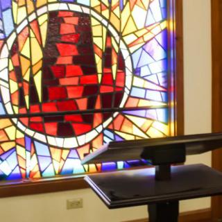 A church podium stands in front of vibrant stained glass artwork.