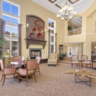 A spacious and well-lit lobby featuring a fireplace, chandelier, and comfortable seating.