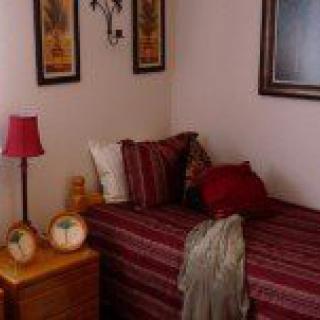 A cozy bedroom corner with striped bedding, decorative pillows, and artwork on the walls.