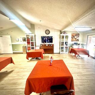 A spacious dining room setup with red tables and a television, creating a welcoming atmosphere.