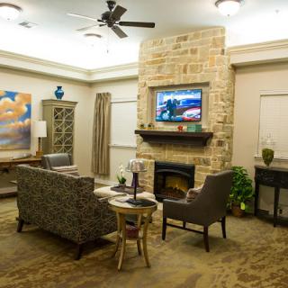 A cozy living room with a stone fireplace, television, and comfortable seating.