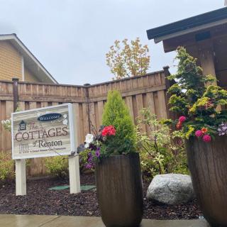 Entrance of a cottage property with planters and flowers next to a wooden fence.