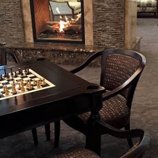 A cozy chess setup by the fireplace, perfect for enjoying a game in a comfortable indoor space.