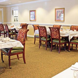 An empty dining room with neatly arranged tables and chairs, featuring warm lighting and elegant decor.