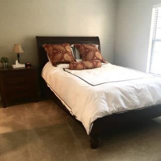 A tidy bedroom with a neatly made bed and nightstand.