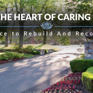 A serene entrance to a place dedicated to rebuilding and recovery, surrounded by lush greenery and vibrant flowers.