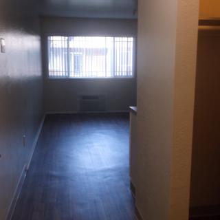 An empty apartment hallway with large windows and dark flooring.