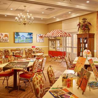 A cozy and colorful interior setting with dining tables, art supplies, and a warm ambiance.