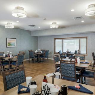 A modern dining room with neatly arranged tables and chairs, illuminated by stylish ceiling lights.