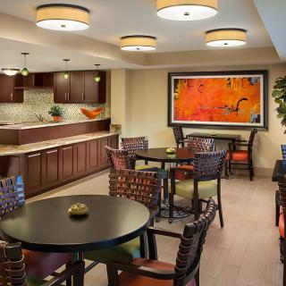 A cozy cafe dining area with modern furniture and colorful artwork on the wall.