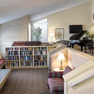 A cozy library space featuring bookshelves and a grand piano.