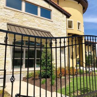 A modern house with a stone facade and an iron fence in front.