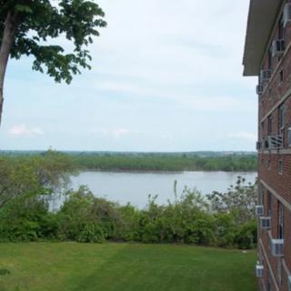 A serene view of a river alongside a building, surrounded by lush greenery and trees.