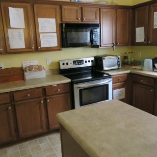 A kitchen with wooden cabinets, featuring a stove, microwave, and countertop appliances.