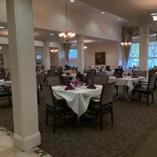 An elegant dining room with set tables and chandeliers.
