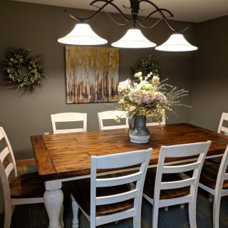 A cozy dining room with a wooden table, white chairs, and elegant lighting.