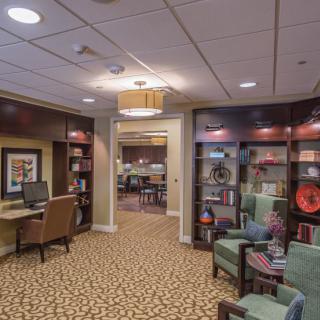 A cozy lobby area with comfortable seating, bookshelves, and a computer workstation.