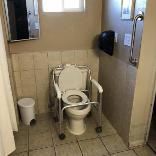 An accessible bathroom equipped with a grab bar and specialized toilet seat for wheelchair users.