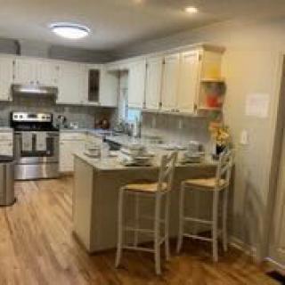 A modern kitchen with white cabinets, an island with bar stools, and stainless steel appliances.