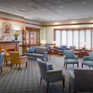 A comfortable waiting area with sofas, chairs, and tables arranged on a carpeted floor.