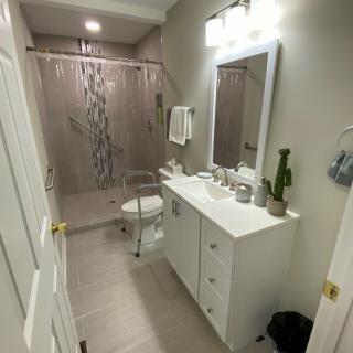 A modern bathroom with a vanity, mirror, and shower area.