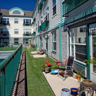 A residential building with balconies and patios adorned with outdoor seating and potted plants.