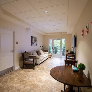 A cozy living room with a sofa, table, and chairs, adorned with wall art and featuring a large window.