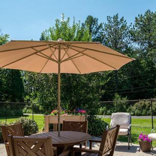 A sunny patio with outdoor furniture and a large umbrella.