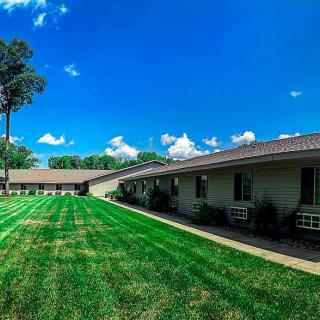 A scenic view of a building with a well-maintained lawn under a clear blue sky.