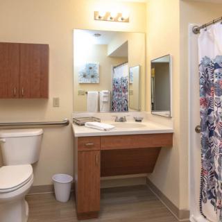 A modern bathroom with a sink, mirror, toilet, and shower curtain.
