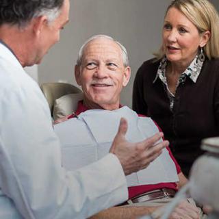 A doctor consulting with an elderly patient and a companion.