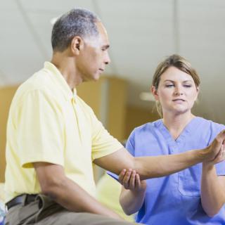 A healthcare professional assists an elderly patient with physical therapy exercises.