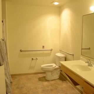 Accessible bathroom with a sink, toilet, and handrail.