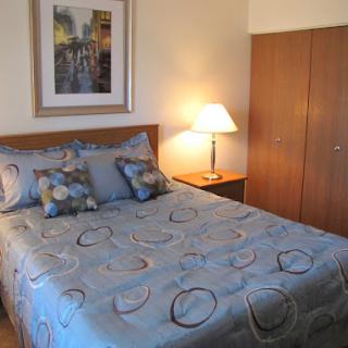 A cozy bedroom featuring a neatly made bed, decorative pillows, and a bedside lamp.
